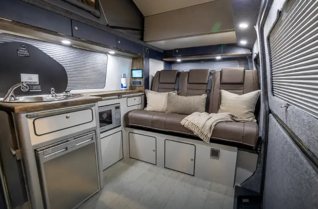 Example camper interior style with fitted kitchen, storage, seating and overhead cabinets