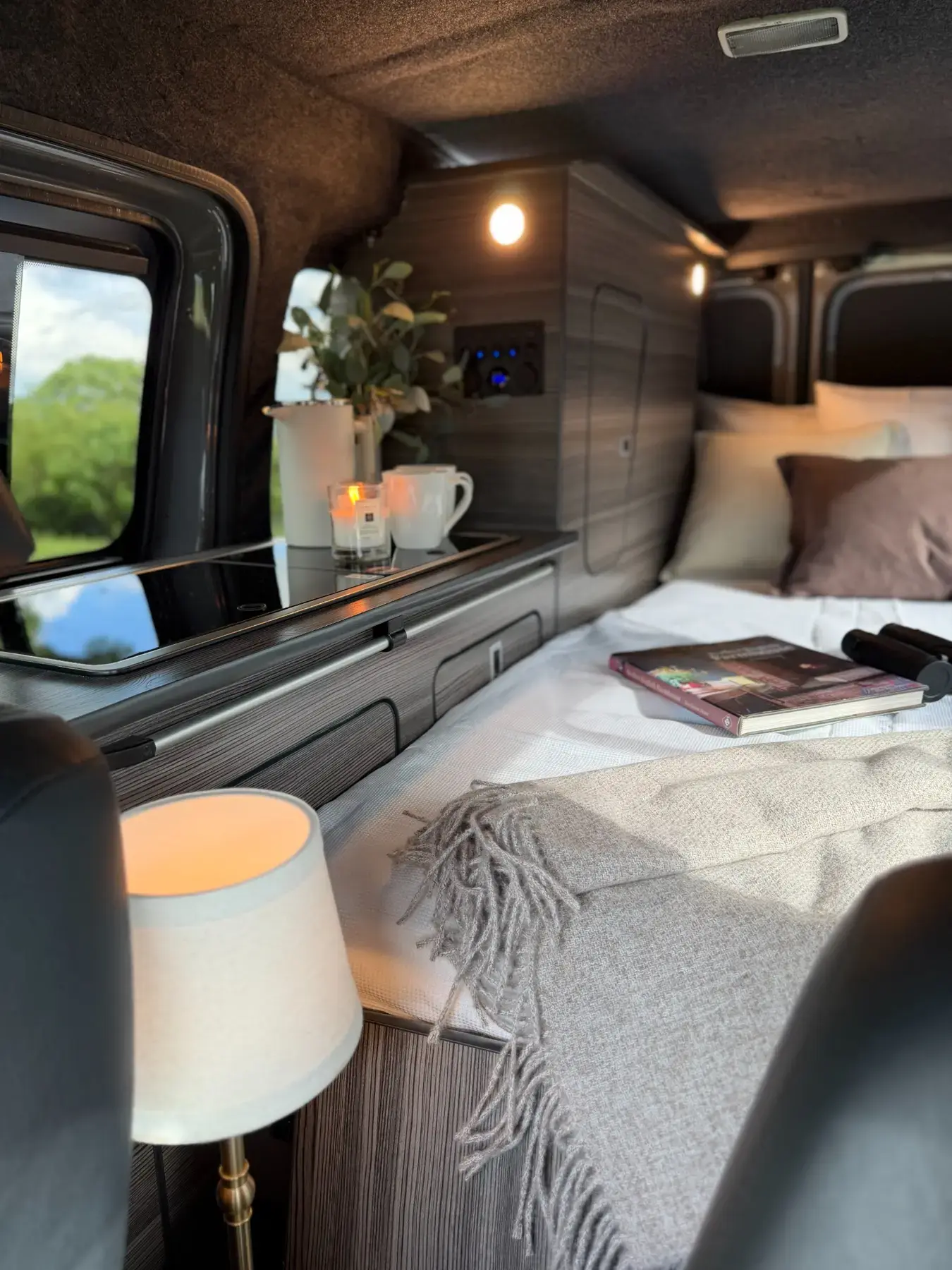 Genuine completed camper bed beside its fitted kitchen and storage units