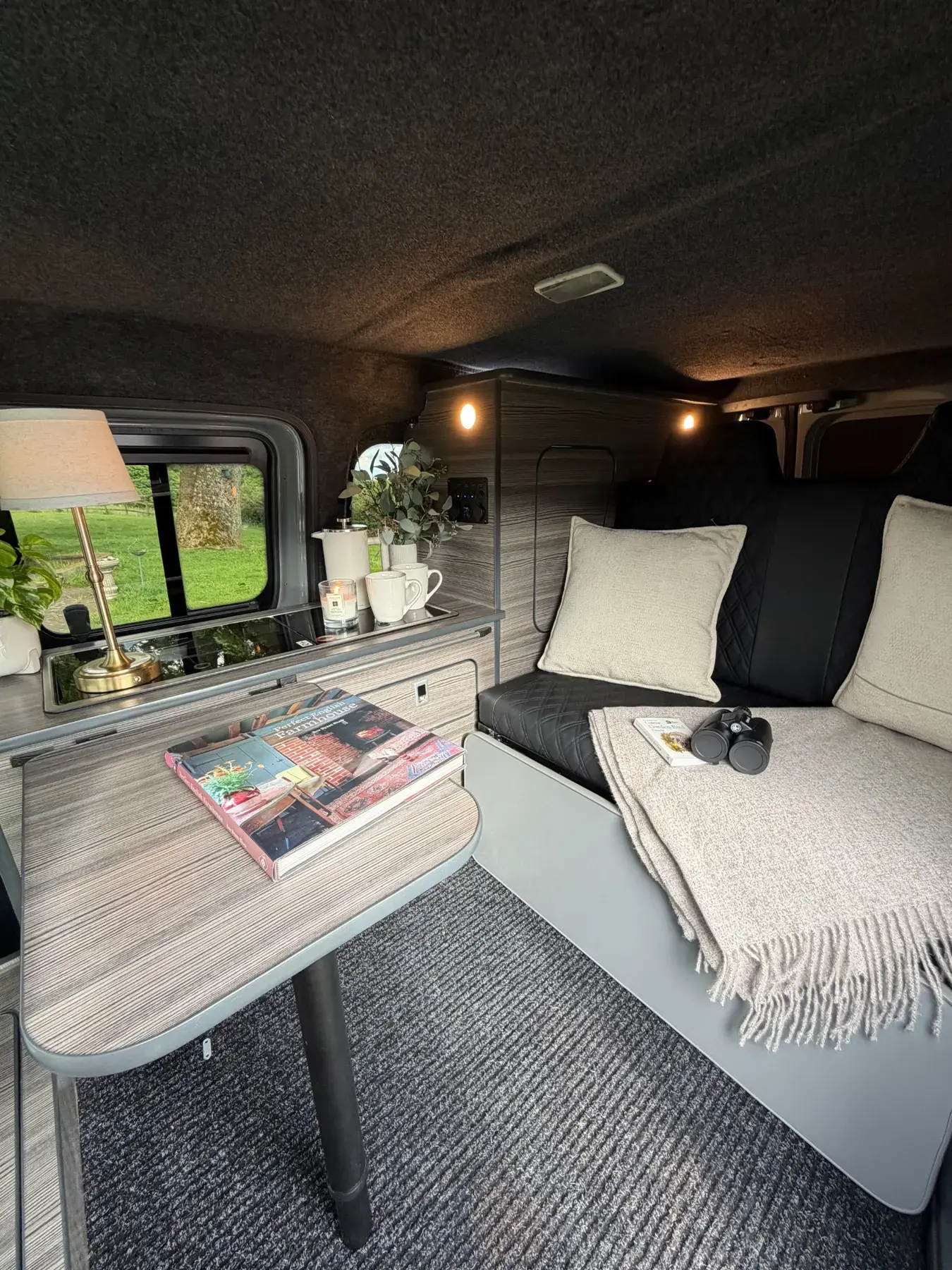 Genuine completed camper interior with tailored black seating, soft furnishings and compact furniture