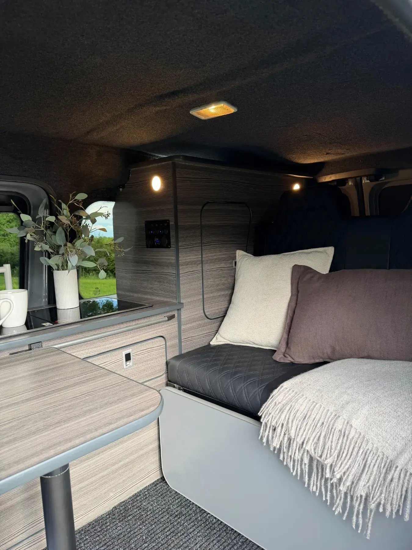 Genuine completed camper seating area with quilted upholstery, cushions and warm lighting